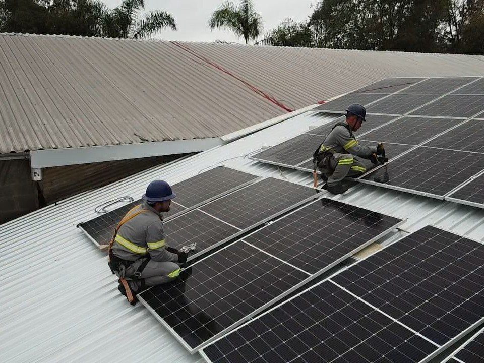 Dois instaladores da Perfect fixando placas solares em um telhado metálico