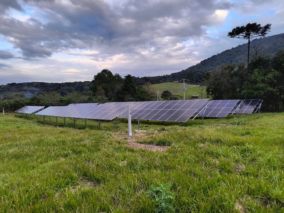 Fileira de placas de uma usina solar em solo, no campo