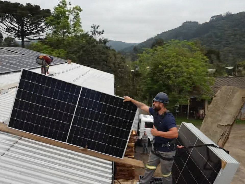 Instalador da Perfect levando uma placa solar até o telhado