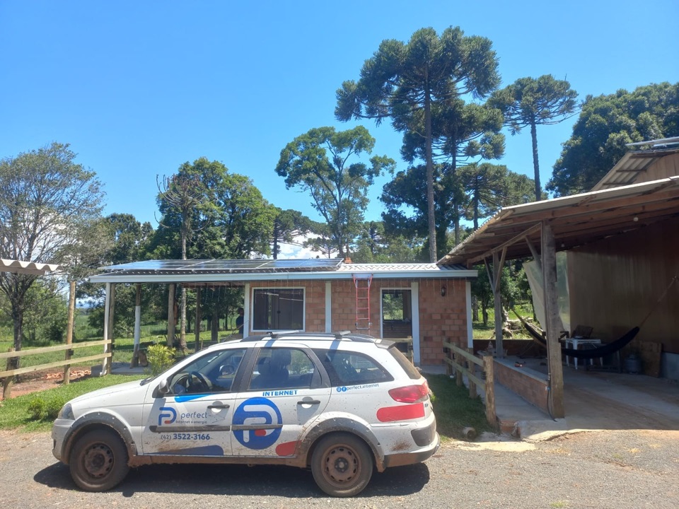 Carro da equipe da Perfect em uma propriedade rural atendida, com placas solares no telhado ao fundo