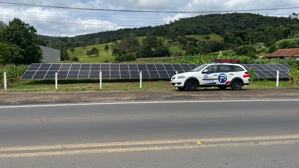 Usina solar em solo à beira da estrada, com o carro da Perfect na frente